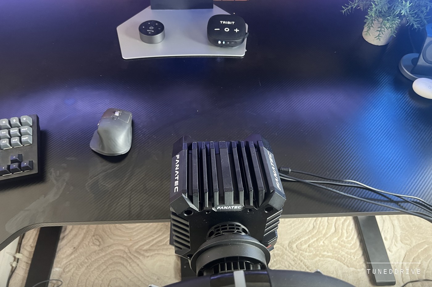 The finned black Fanatec CSL DD base seen from above on a desk, cables running from its back
