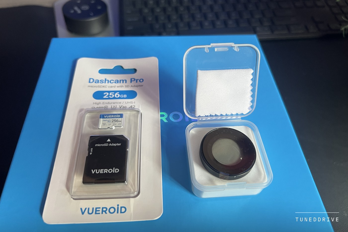 A Vueroid 256 GB Dashcam Pro microSD card in its retail pack beside a CPL filter in a clear case, on the Vueroid box