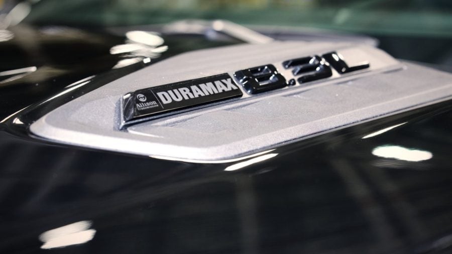 Duramax 8.3L and Allison badges on a silver hood insert on a black truck.