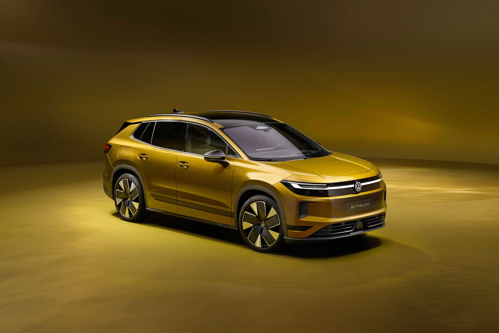 Gold Volkswagen ID. Tiguan viewed from the front and side in a gold studio.