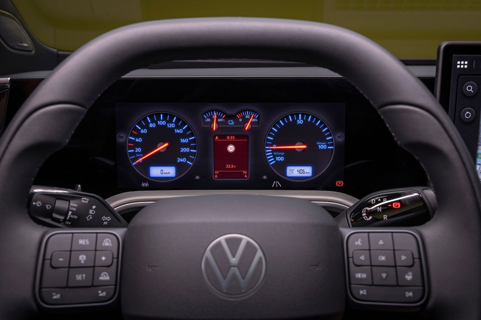 Volkswagen steering wheel with physical buttons in front of a digital display with circular gauges.